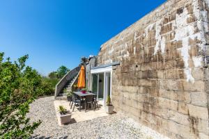 uma parede de tijolos com uma mesa e um guarda-chuva em Blockhaus 44 em Ver-sur-Mer