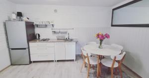 a kitchen with a table with chairs and a refrigerator at Apartament OLTO Mikołajki in Mikołajki