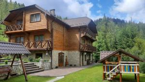 a large wooden house with a playground in front of it at Respect in Mykulychyn