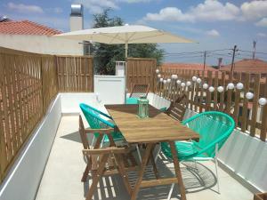 una mesa de madera y sillas con una sombrilla en el balcón en Angel's House, en Quinta do Anjo