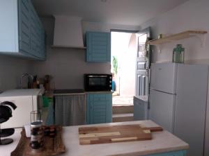 cocina con armarios azules y nevera blanca en Angel's House, en Quinta do Anjo