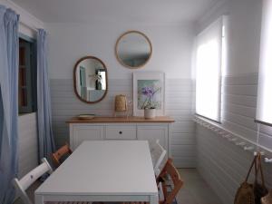 a white dining room with a table and a mirror at Angel's House in Quinta do Anjo