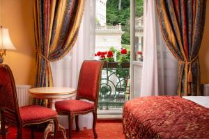 カルロヴィ・ヴァリにあるアクア マリーナのベッドと椅子、窓が備わるホテルルームです。