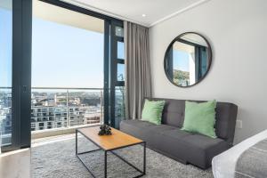 een woonkamer met een bank en een spiegel bij 16 on Bree Luxury Apartments in Kaapstad