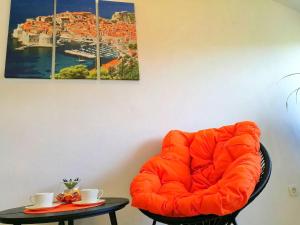 einen orangenen Stuhl in einem Zimmer mit einem Tisch in der Unterkunft Apartments Kola in Banići