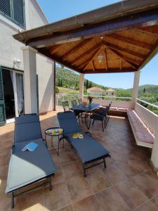 een patio met stoelen, een tafel en een houten dak bij Apartments Kola in Banići