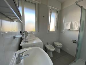 a white bathroom with a toilet and a sink at Appartamenti al Cigno in Lignano Sabbiadoro