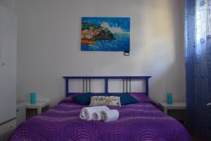 a bedroom with a purple bed with two towels on it at A Due Passi da Erice B&B in Erice