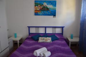 a bedroom with a purple bed with towels on it at A Due Passi da Erice B&B in Erice