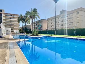 una gran piscina azul con palmeras y edificios en Alea Rentals - Acquamarina, en La Pineda