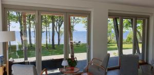 uma sala de estar com portas de vidro deslizantes com vista para a água em Guest House Vidlauči em Skulte