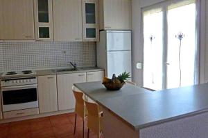 una cucina con armadi bianchi e un'isola con piano di lavoro di Havikee, private beach villa! a Ormos Panagias