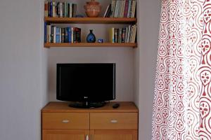 una televisione su un comò di legno con mensola per libri di Havikee, private beach villa! a Ormos Panagias