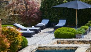 un patio con tumbonas y una sombrilla junto a la piscina en Domaine des Andéols en Saint-Saturnin-dʼApt