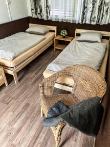 a room with two beds and a wicker chair at Camp Alpa in Ostrovačice