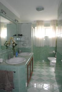 a green bathroom with two sinks and a toilet at Summer Beach Rooms in Fontane Bianche