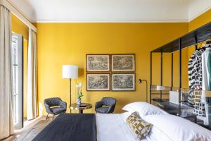 1 dormitorio con paredes amarillas, 1 cama y sillas en 4F Boutique Hotel Florence, en Florencia