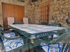 a glass table with chairs and a stone wall at Dammuso Il tramonto di Nica' in Scauri