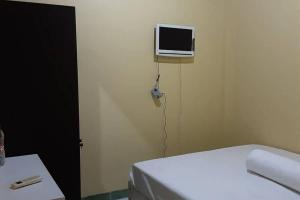 a bedroom with a bed and a tv on the wall at Guest House Syariah LP3B Brebes RedPartner in Brebes