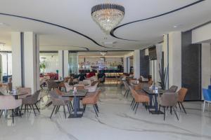 a restaurant with tables and chairs and a chandelier at Hotel Vivas in Durrës