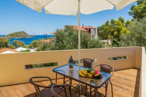 una mesa con fruta en un balcón con sombrilla en Armiriki Holiday Home, en Agios Nikolaos