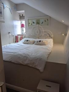 Pinfold Holiday Cottage في سكيبتون: غرفة نوم بسرير أبيض مع لوحة للرأس