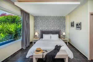 ein Schlafzimmer mit einem Bett und einem großen Fenster in der Unterkunft Sunny Villas Resort & Spa in Chaniotis
