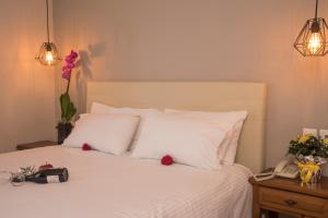 a bedroom with a white bed with a phone and flowers at Filoxenia Hotel in Volos