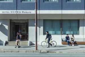 a man walking a bike in front of a building at Hotel Nupka in Obihiro