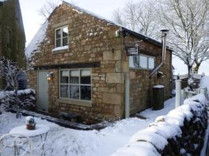 a stone house in the snow with a table at Pinfold Holiday Cottage in Skipton