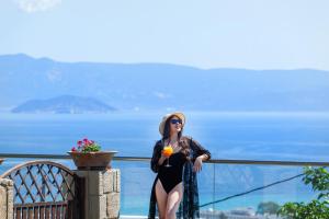 ハニオティスにあるSunny Villas Resort & Spaの女性がバルコニーに立ってドリンクを飲みながら