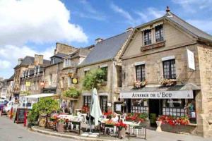 un ancien bâtiment avec des tables et des chaises dans une rue dans l'établissement La roseraie de L arguenon, spacieux appartement centre ville, à Jugon Les Lacs