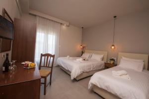 a hotel room with two beds and a table and chair at Filoxenia Hotel in Volos