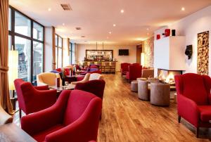 una sala de espera con sillas rojas y chimenea en Hotel Bavaria, en Zwiesel