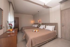 two beds in a hotel room with oranges on a tray on the bed at Filoxenia Hotel in Volos