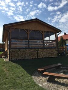 drewniany pawilon z stosem kłód w obiekcie Siedlisko nr 4A nad jeziorem Skarlińskim, jezioro, mazury, domki letniskowe w mieście Kurzętnik