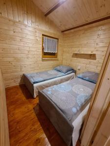 a room with two beds in a wooden cabin at Siedlisko nr 4A nad jeziorem Skarlińskim, jezioro, mazury, domki letniskowe in Kurzętnik