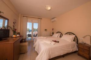 a bedroom with a bed and a television and a balcony at Filoxenia Hotel in Volos