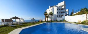 een zwembad voor een gebouw met uitzicht op de oceaan bij Exclusivo apartamento 2 dormitorios in Torrox Costa