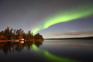 an aurora over a lake at night with the stars at Wilderness Hotel Nellim & Igloos in Nellimö