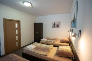 a room with three beds in a room with a door at Penzion Toscana in Nitra