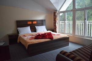 a bedroom with a bed with a red dress on it at Cedar Vista Resort in Kāgān