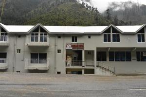 a large white building with a mountain in the background at Cedar Vista Resort in Kāgān