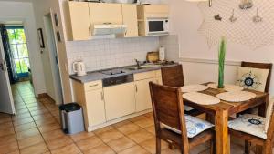 eine Küche mit einem Tisch, Stühlen und einem Waschbecken in der Unterkunft Ferienwohnung Urte in Putgarten , Kap Arkona Rügen in Putgarten