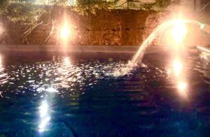a fountain in a pool at night with lights at Locanda Etrusca in Bibbona