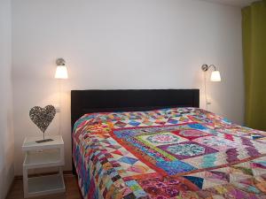 a bedroom with a bed with a colorful quilt on it at Penzion Malina in Hronská Dúbrava