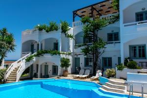 a villa with a swimming pool in front of a building at Kurmulis Studios in Stalos