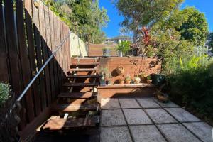 a garden with a wooden fence and a wooden bench at Cozy self-contained unit surrounded by nature in Goonellabah