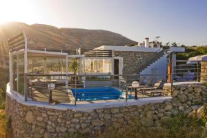 a house with a pool and a stone wall at Serenity Villa in Karpathos