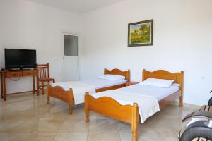 two beds in a room with a tv and a desk at Pellumb Apartments in Ksamil